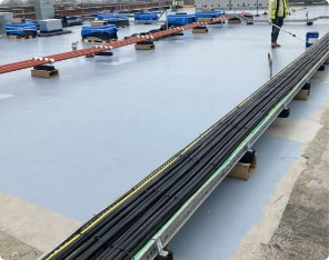 Flat roof with smooth grey liquid membrane and cable trays