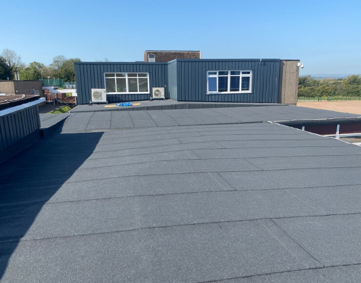 Flat roof membrane installation on commercial building with metal cladding