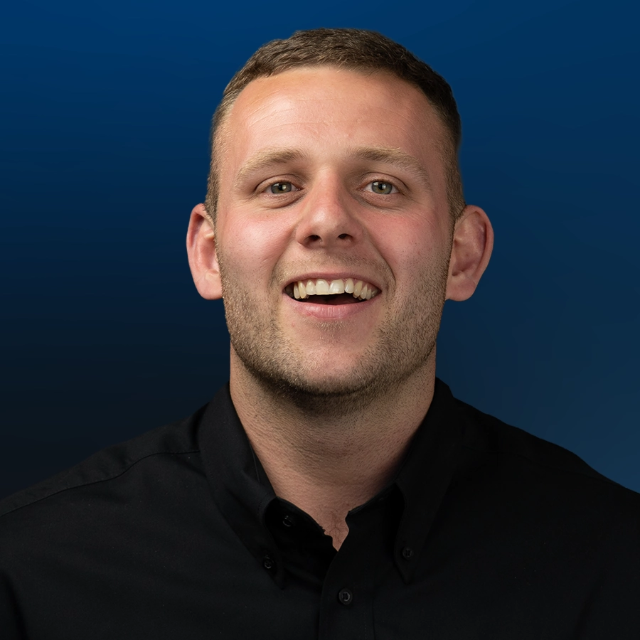 Professional headshot of smiling man wearing black polo shirt