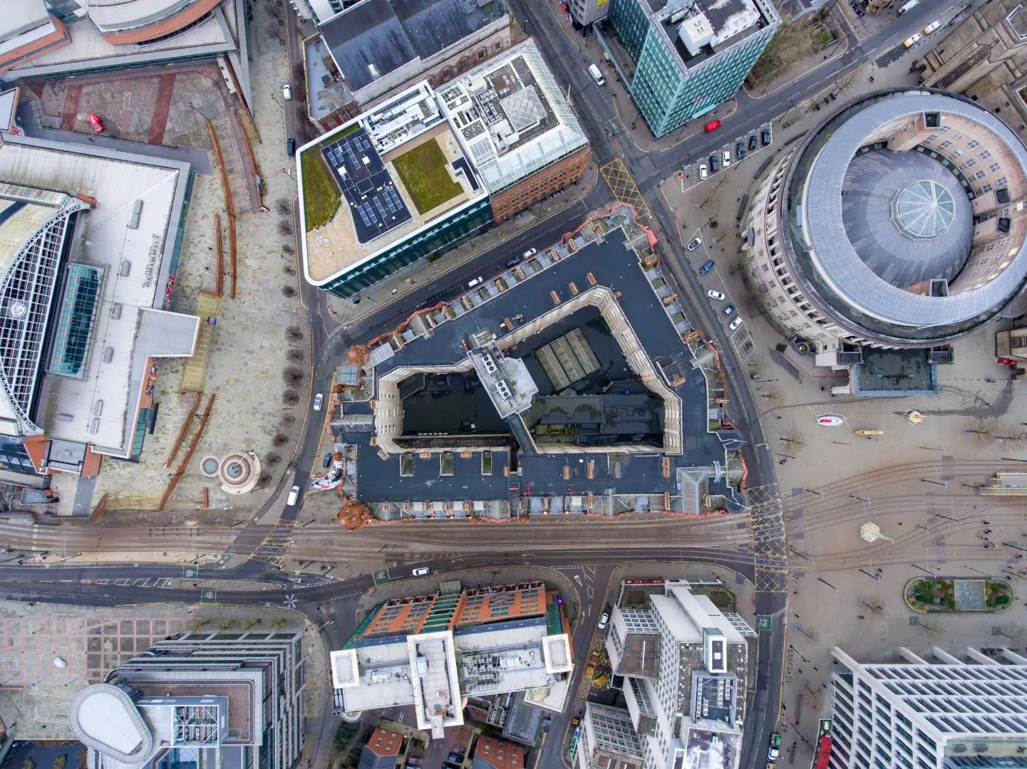 Garland UK’s Journey to Net Zero: Sustainability Report 2023 Aerial view of a city block showing roads, modern buildings with flat roofs, a circular building and a central courtyard, with traffic and pedestrians visible