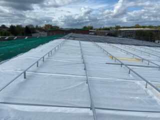 Roof installation phase showing mounting rail system in place part of Garland UK’s R-MER CLAD and Solarise installation.