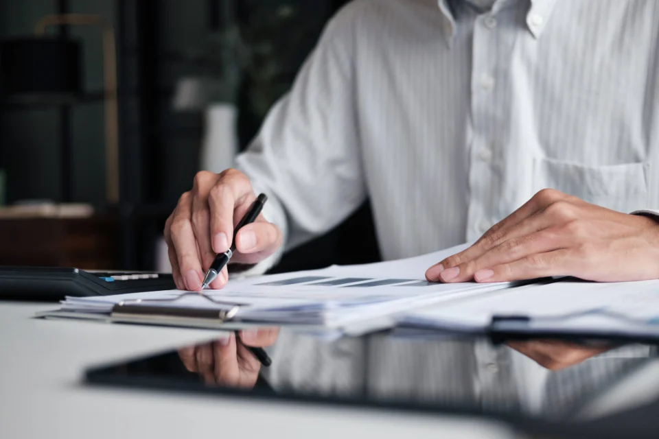 Professional man signing documents at desk with pen and papers