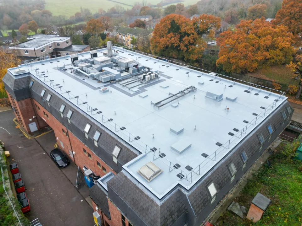 Aerial view of modern flat roof commercial building with HVAC systems and autumn trees