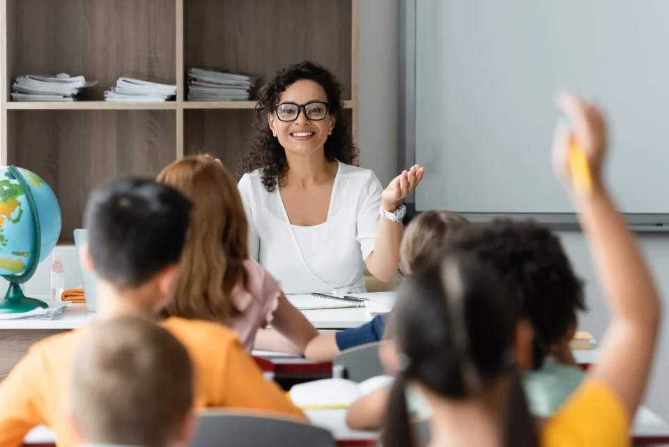 Teacher engaging students in classroom lesson with raised hands