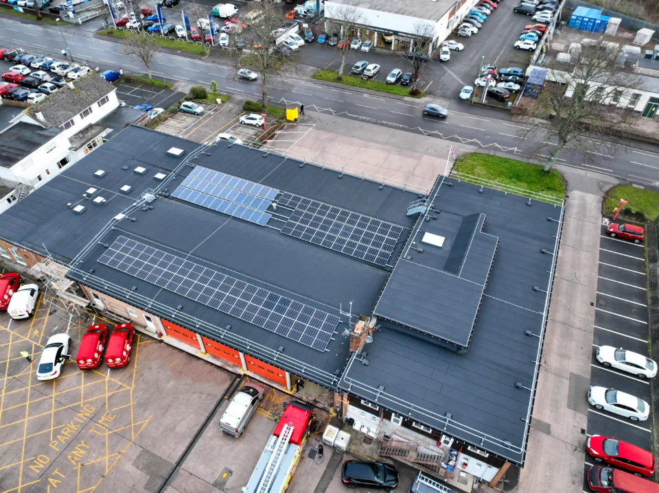 Aerial view fire station rooftop solar panels parking lot vehicles