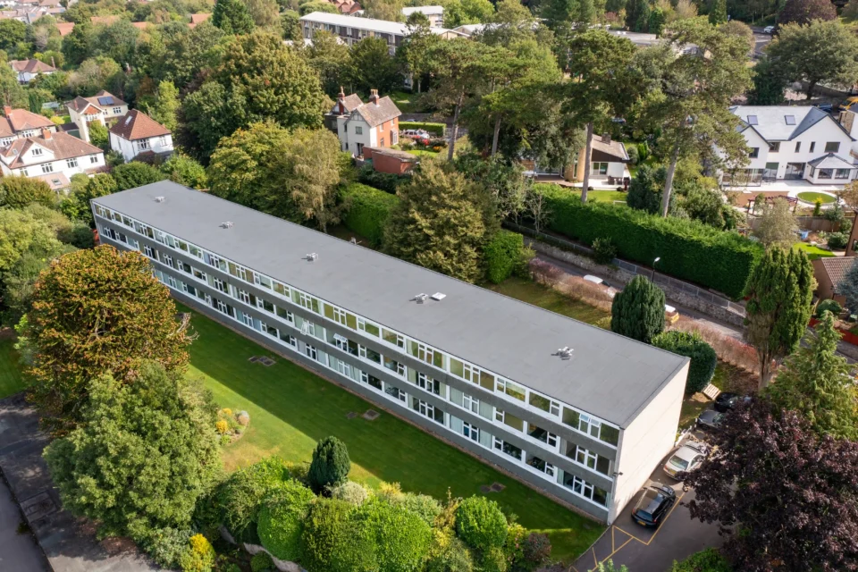 Aerial view of modern residential apartment building surrounded by green landscape and trees