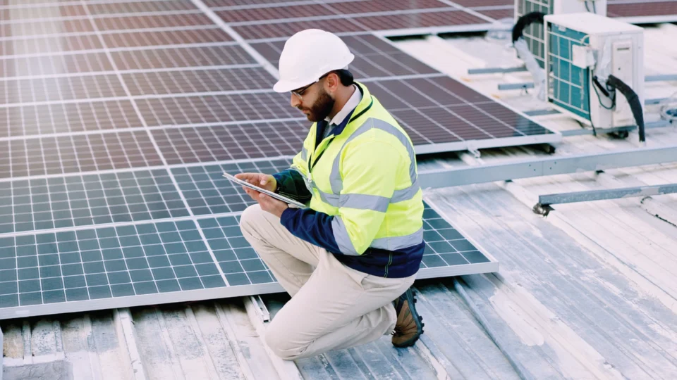Solar panel technician inspecting rooftop photovoltaic system installation