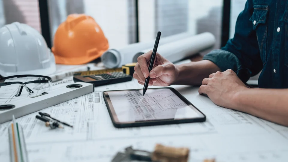 Construction worker using digital tablet to review building plans and blueprints