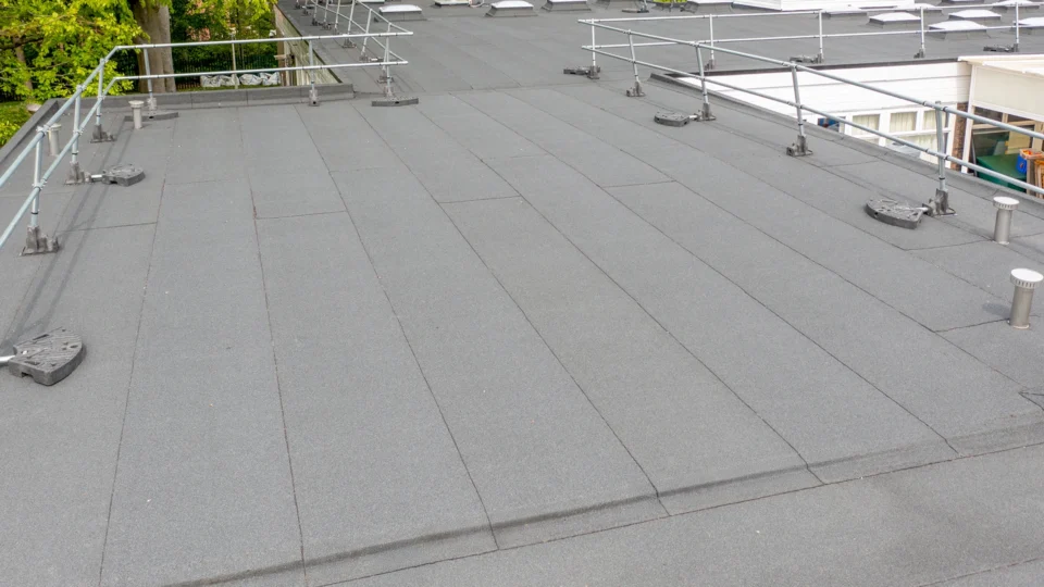 Flat roof with gray membrane, safety railings, and metal fixtures installed