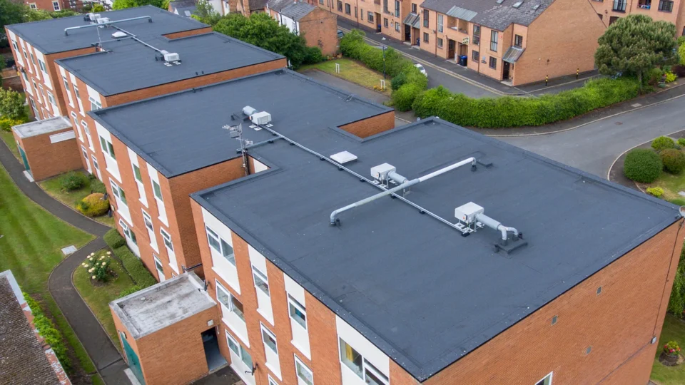 Aerial view of flat roof with HVAC systems and piping on brick building