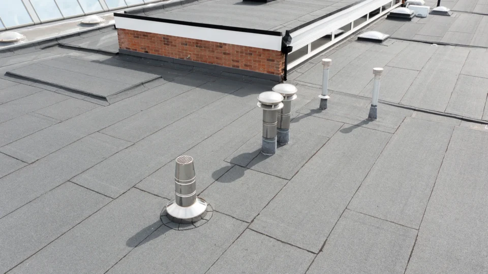 Commercial flat roof with membrane, ventilation pipes, and brick structure