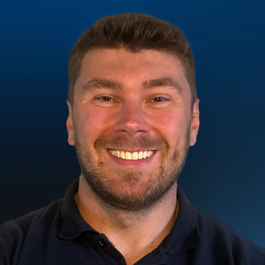 Smiling man with beard wearing dark polo shirt against blue background