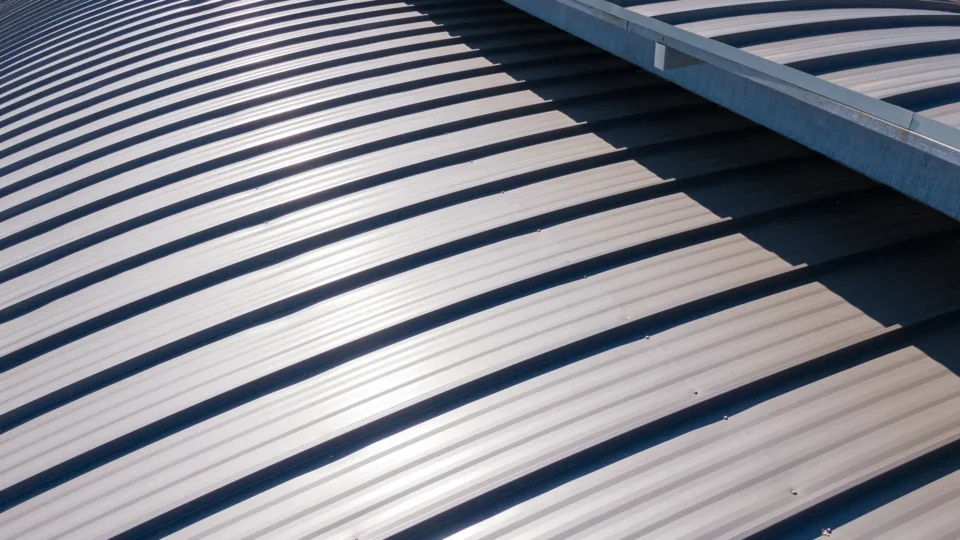 Corrugated metal roof panels with parallel ridges and deep shadows