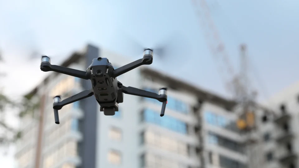 Black drone hovering above urban residential buildings cityscape