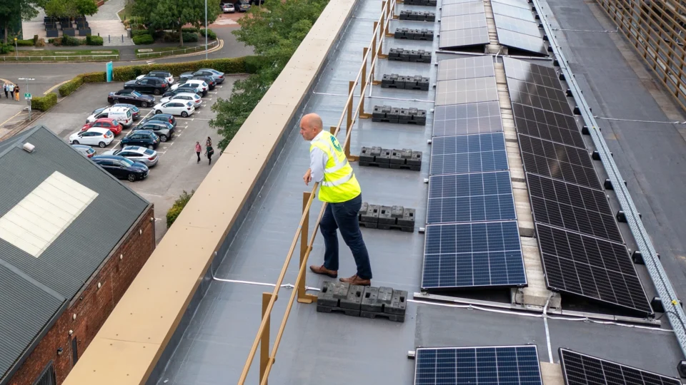 Worker in safety vest inspecting rooftop solar panel installation