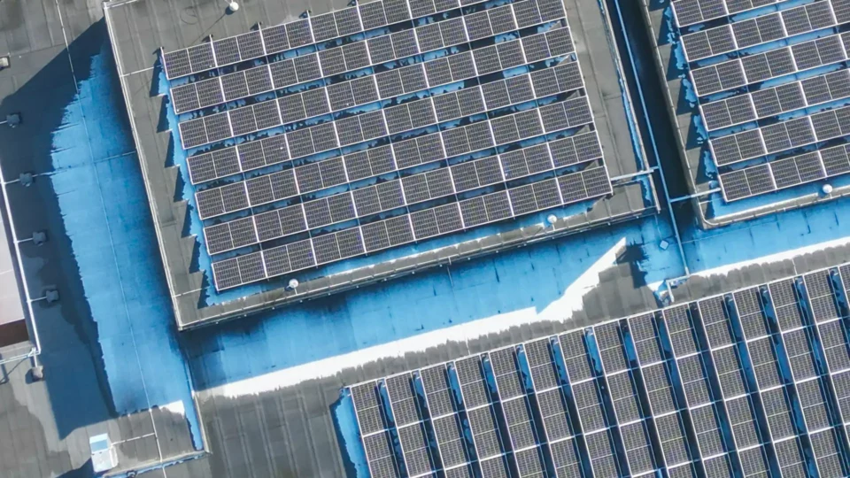 Aerial view of rooftop solar panels on blue industrial building structure