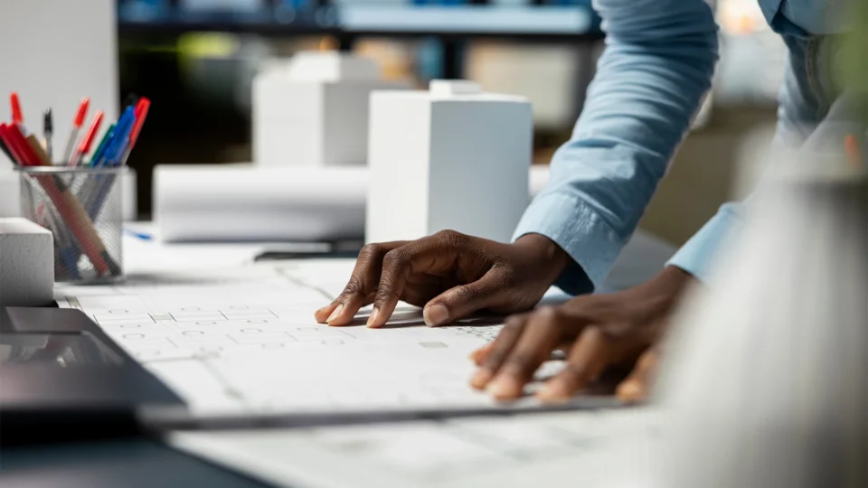 Architect reviewing blueprint plans at desk with design models