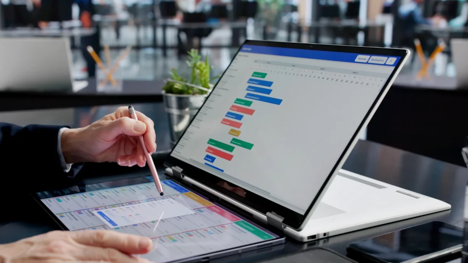 Business professional reviewing Gantt chart schedule on laptop and tablet devices