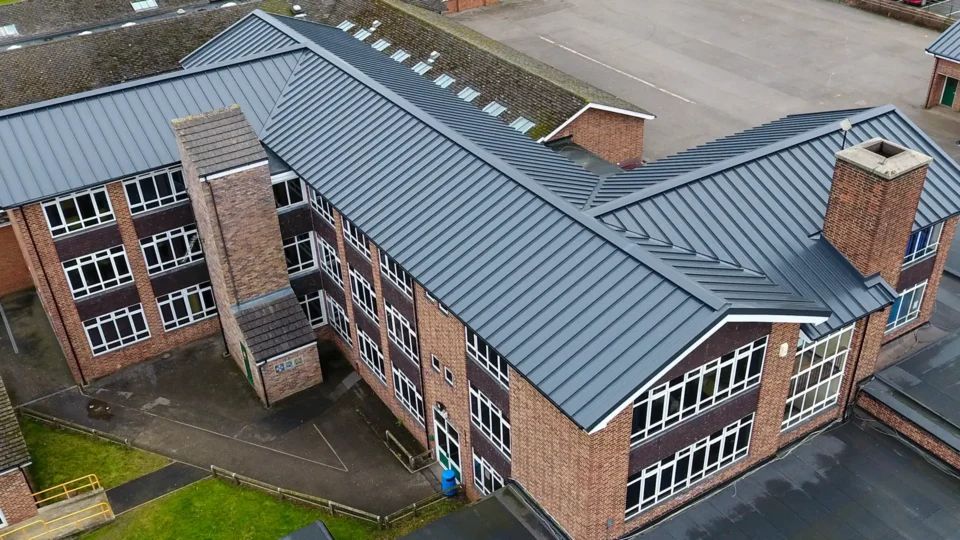 Aerial view of brick school building with modern metal roof panels