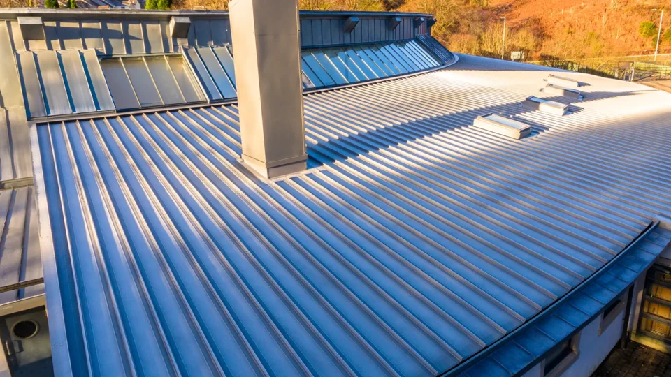 Modern metal roofing installation with blue corrugated panels and skylights