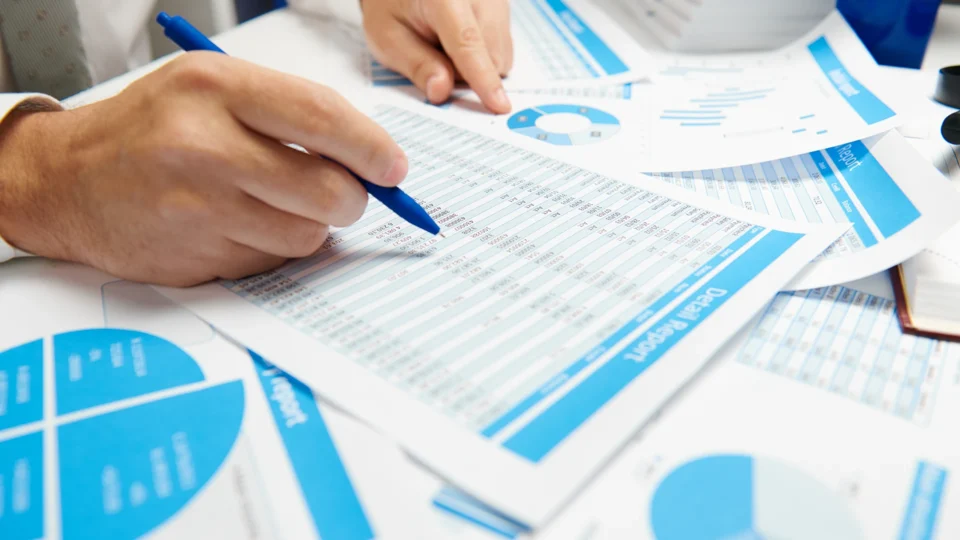 Business professionals analyzing financial data and charts with blue pen