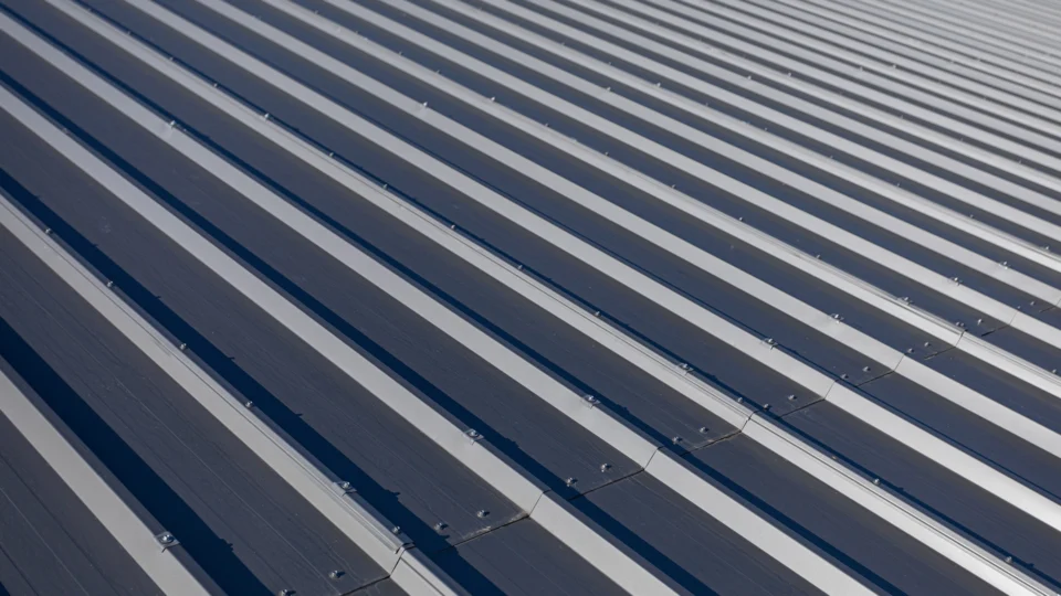 Corrugated metal roofing with alternating light and dark ridges casting shadows