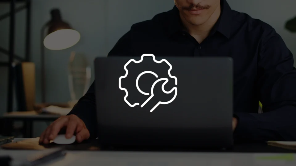 Man working on laptop displaying gear and wrench maintenance icon