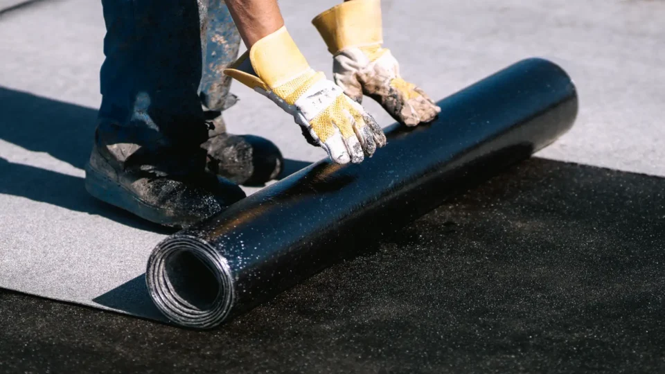Worker installing black waterproof membrane with UV protection coating