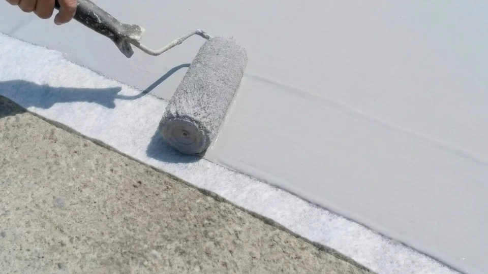 Paint roller applying white coating to concrete surface