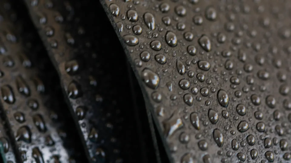 Water droplets beading on dark waterproof material surface