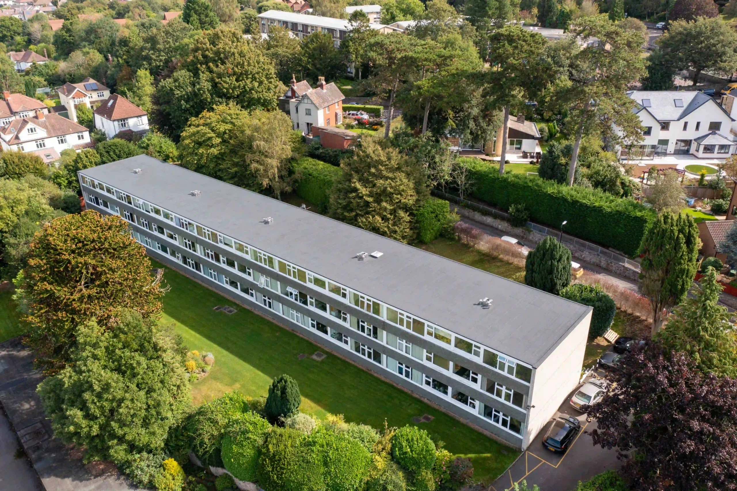 Aerial view of modern residential apartment building surrounded by green landscape and trees